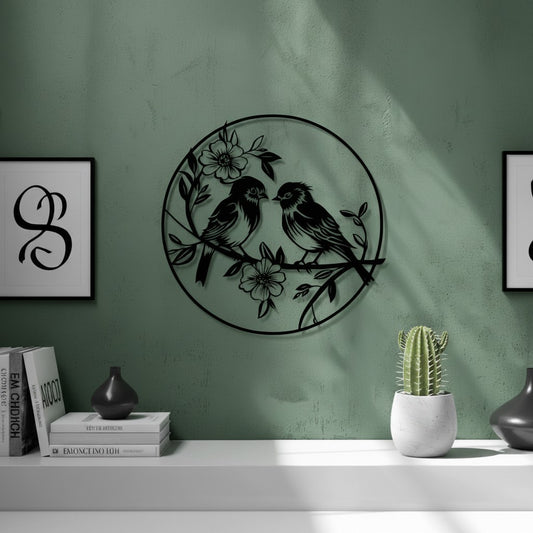Black 3D printed circular birds with flowers wall art mounted on a sage green textured wall, with white floating shelf, stacked books, cactus and ceramic vase below, UK made